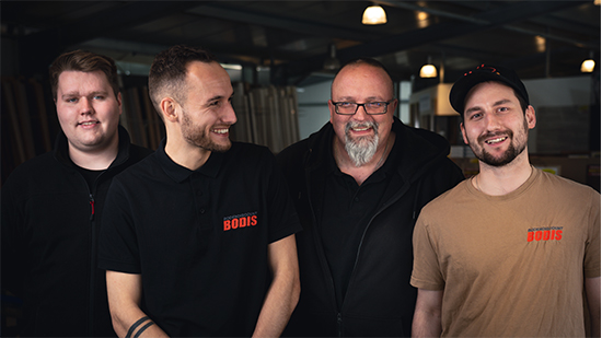 Teamfoto BODIS Münster Vier freundlich lächelnde Mitarbeiter stehen nebeneinander.